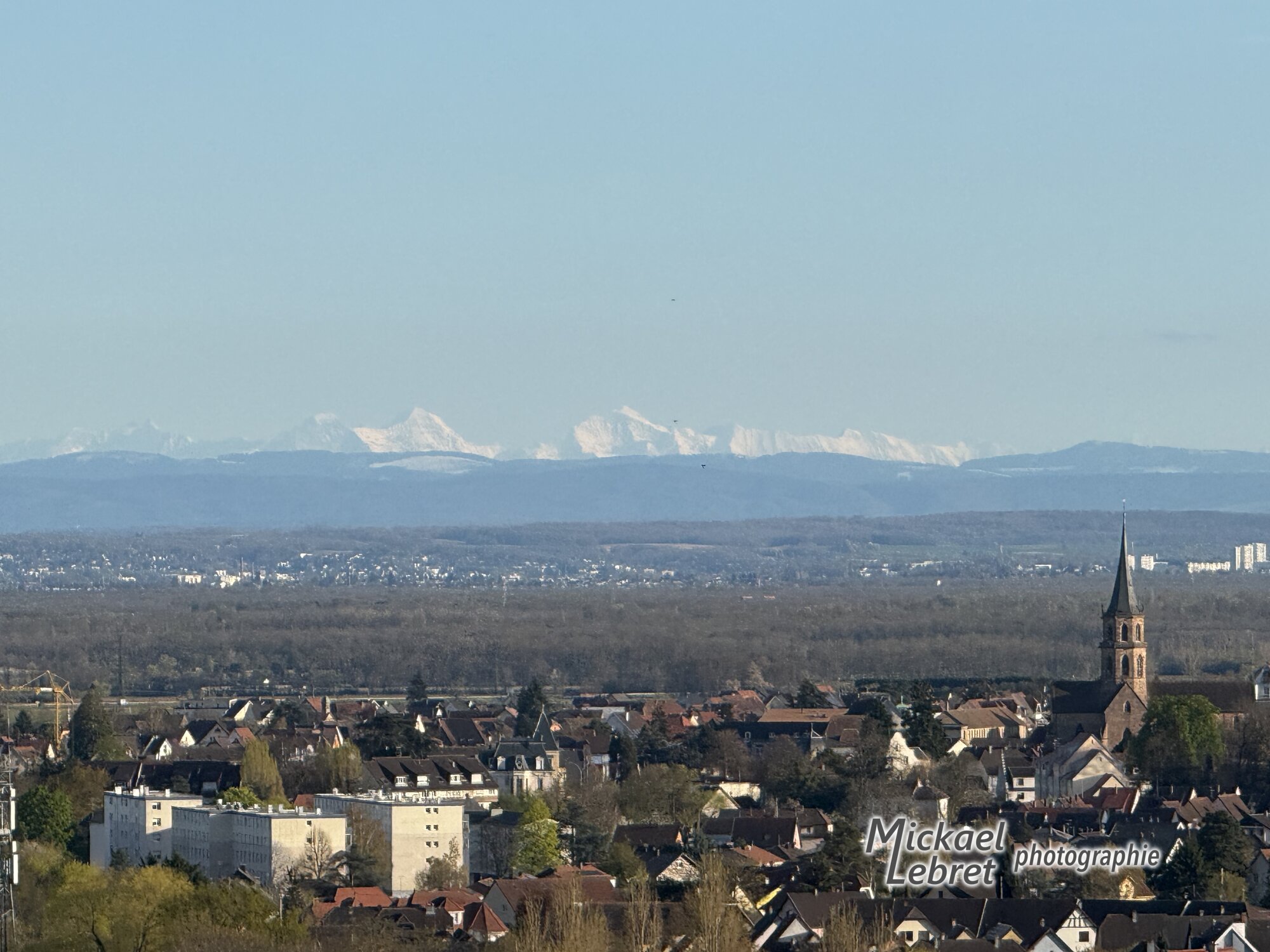 Au téléobjectif, les Alpes bernoises enneigées au-dessus de la ligne du Jura, Soultz au premier plan