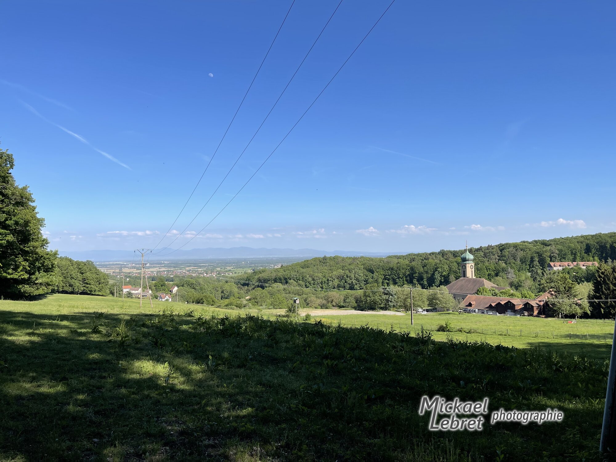 La basilique de Thierenbach en contrebas, la plaine d'Alsace et la Forêt-Noire à l'horizon