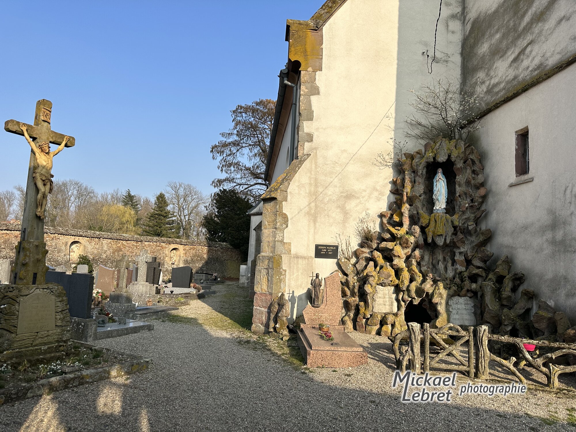 Dans le cimetière fortifié, le grand crucifix et la grotte de Lourdes adossée à l'église