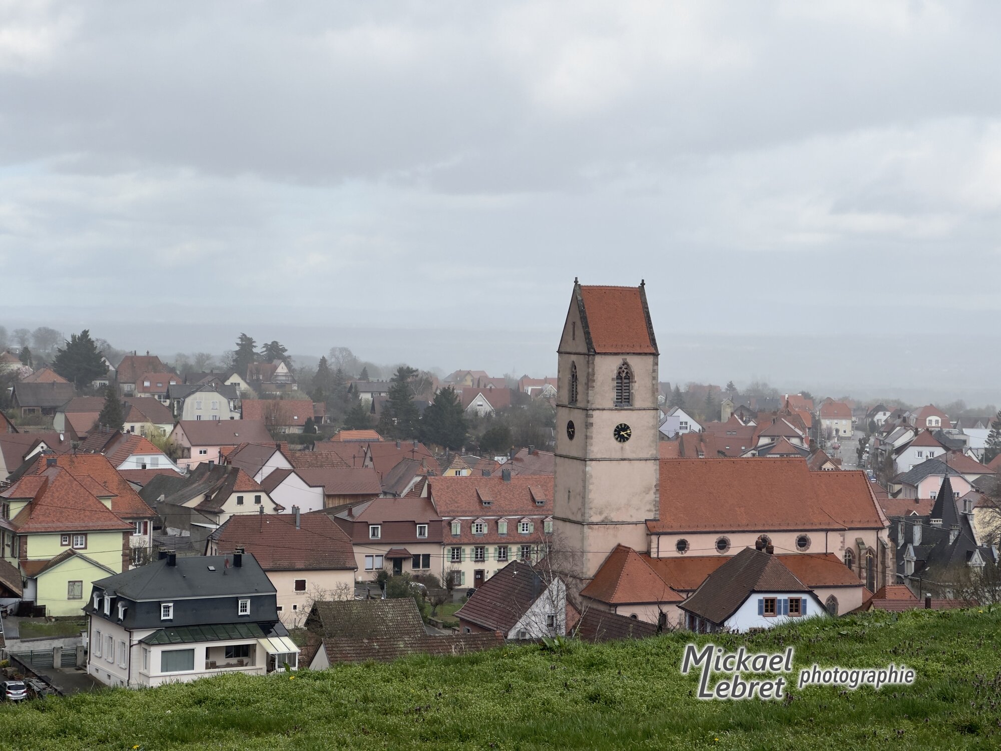 Wattwiller et son église au milieu des toits, la plaine dans la brume